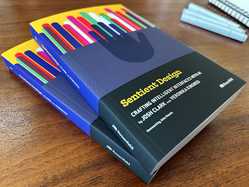 Sentient Design books on a wood-grain surface