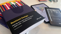 Sentient Design paperbacks next to kindle and ipad editions on a marble surface